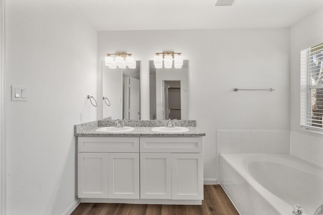 bathroom featuring vanity, wood-type flooring, and a tub