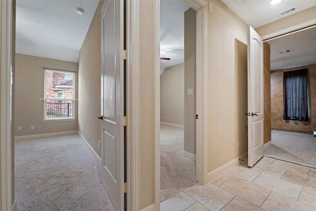 hall with light colored carpet, visible vents, and baseboards