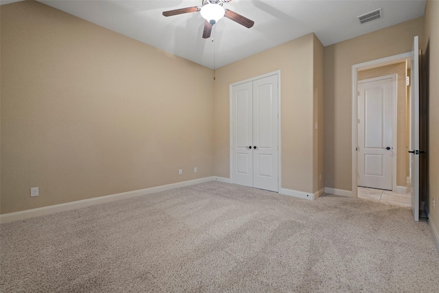 unfurnished bedroom featuring a closet, light colored carpet, visible vents, ceiling fan, and baseboards