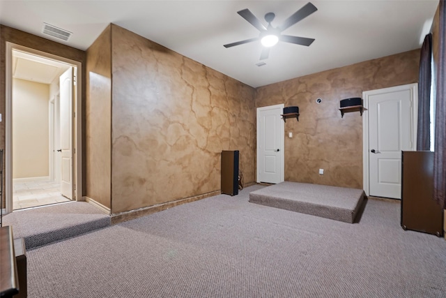 carpeted spare room with visible vents and a ceiling fan