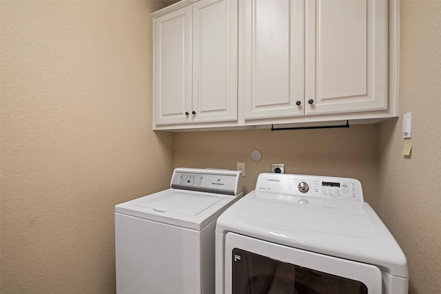 laundry room featuring cabinet space, washer and dryer, and a textured wall