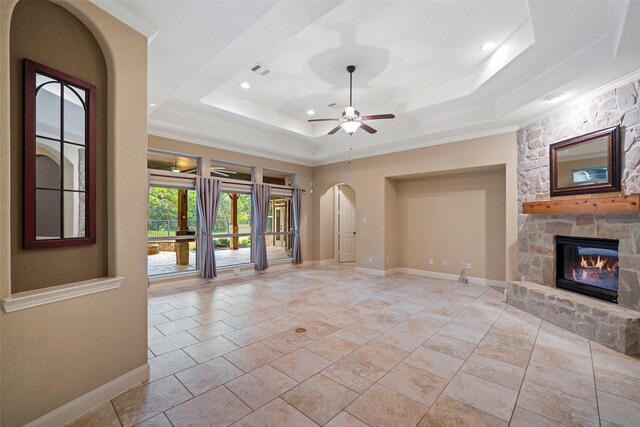 unfurnished living room featuring a raised ceiling, crown molding, ceiling fan, and a fireplace