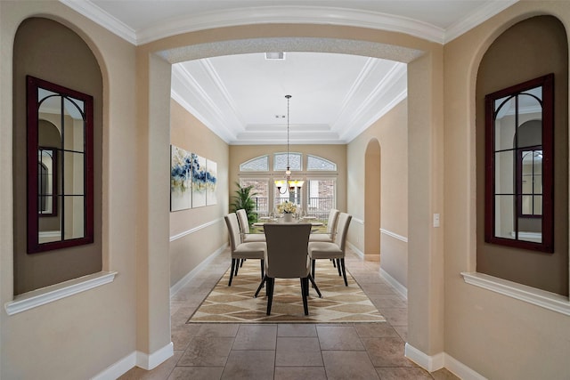 dining space with crown molding, a tray ceiling, and a chandelier