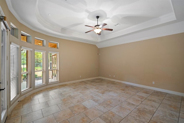 spare room with a raised ceiling, crown molding, and baseboards