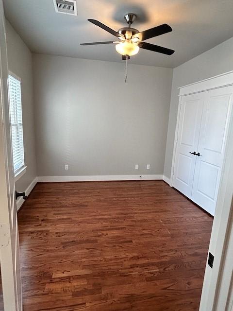 unfurnished bedroom with multiple windows, dark hardwood / wood-style flooring, and ceiling fan