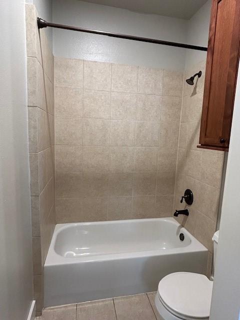 bathroom with tile patterned flooring, tiled shower / bath combo, and toilet