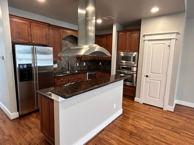 kitchen featuring island exhaust hood, appliances with stainless steel finishes, dark stone counters, sink, and a kitchen island