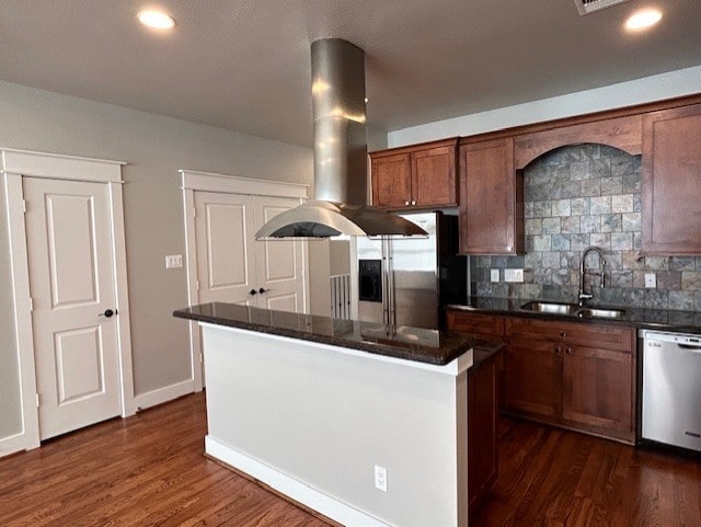 kitchen with sink, stainless steel appliances, island exhaust hood, decorative backsplash, and a kitchen island