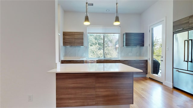 kitchen with sink, decorative backsplash, hanging light fixtures, light hardwood / wood-style floors, and stainless steel appliances