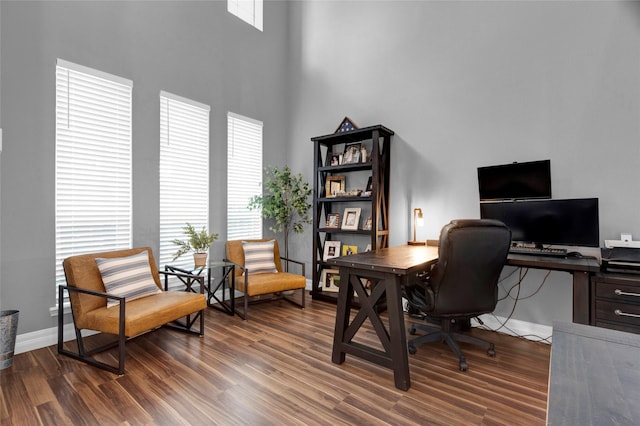 home office with dark hardwood / wood-style flooring and a towering ceiling