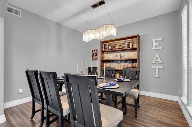 dining space with dark hardwood / wood-style floors and an inviting chandelier