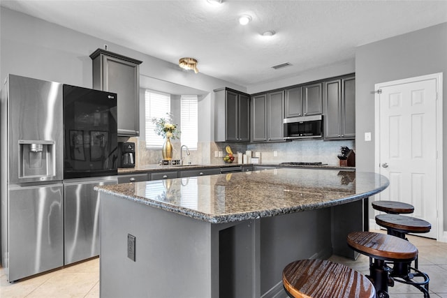 kitchen featuring a kitchen island, black fridge, and dark stone countertops