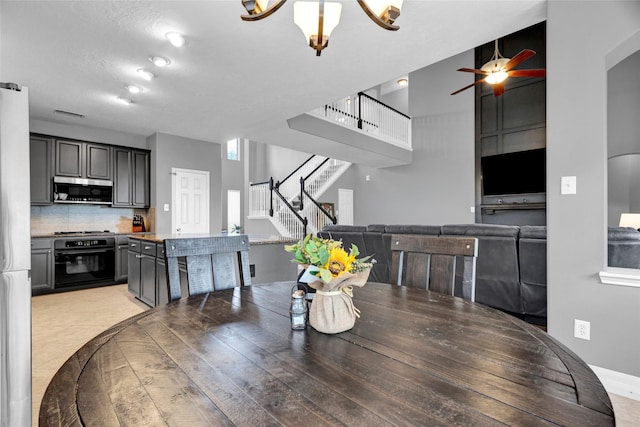 dining space featuring ceiling fan with notable chandelier