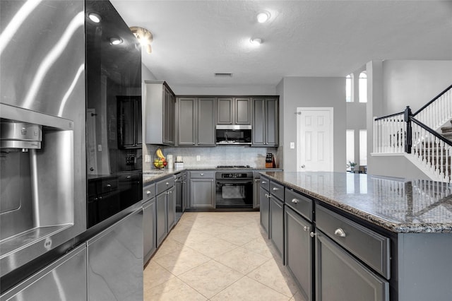 kitchen with gray cabinets, dark stone countertops, and appliances with stainless steel finishes