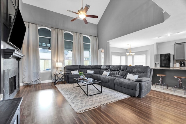 living room featuring a wealth of natural light, a fireplace, dark hardwood / wood-style floors, and ceiling fan with notable chandelier