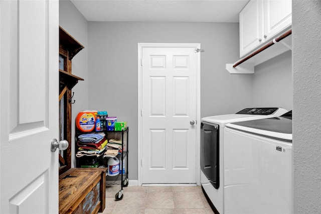 washroom featuring cabinets, light tile patterned floors, and washing machine and clothes dryer