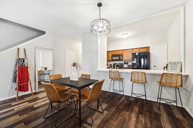 dining space featuring dark hardwood / wood-style flooring, an inviting chandelier, and sink