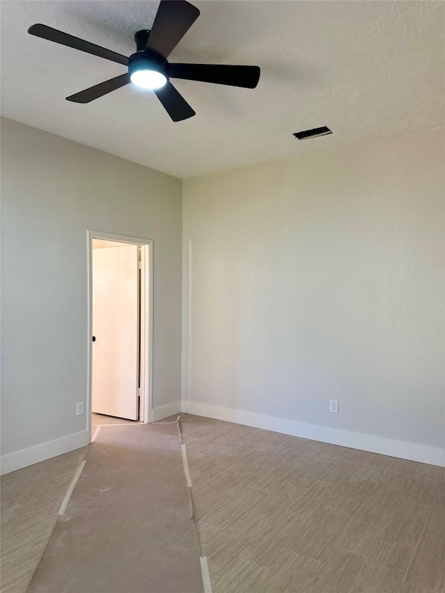 unfurnished room with ceiling fan and a textured ceiling