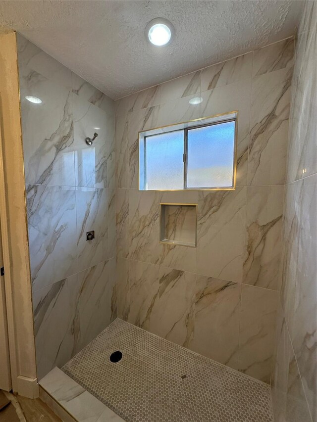 bathroom featuring a tile shower and a textured ceiling