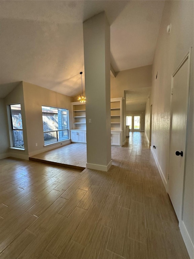 interior space featuring hardwood / wood-style floors, built in shelves, lofted ceiling, and an inviting chandelier