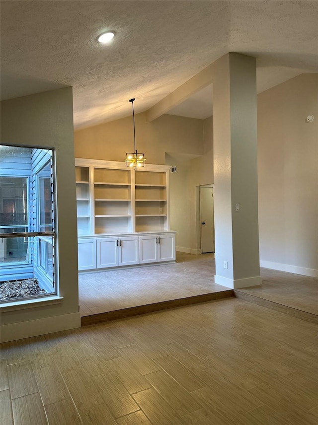 unfurnished living room featuring a notable chandelier, light hardwood / wood-style floors, lofted ceiling, and a textured ceiling