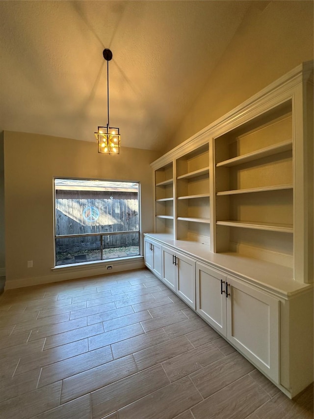 unfurnished dining area featuring an inviting chandelier and vaulted ceiling