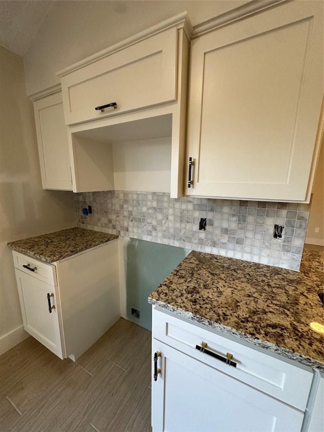 kitchen featuring decorative backsplash, white cabinets, and dark stone counters