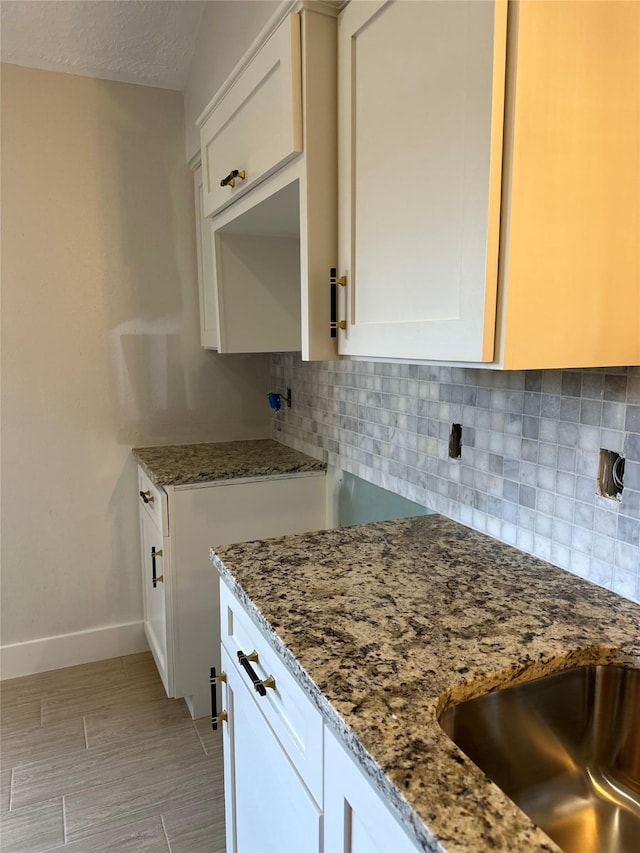 kitchen featuring backsplash, dark stone countertops, white cabinets, and a textured ceiling