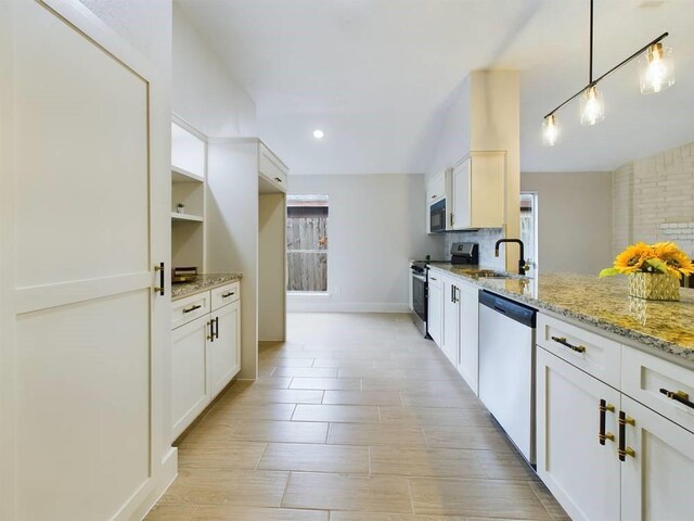 kitchen featuring sink, appliances with stainless steel finishes, white cabinetry, light stone counters, and decorative light fixtures