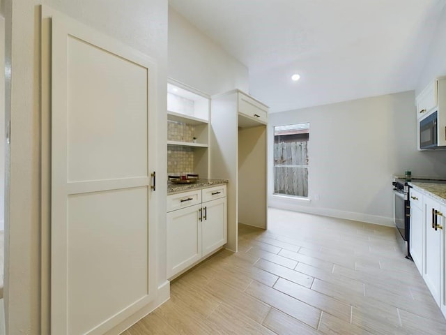 kitchen with light stone counters, white cabinetry, and stainless steel range with electric cooktop