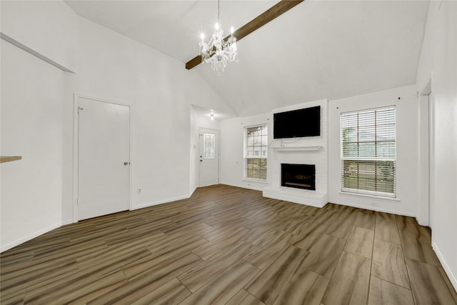 unfurnished living room featuring high vaulted ceiling, a chandelier, and a brick fireplace