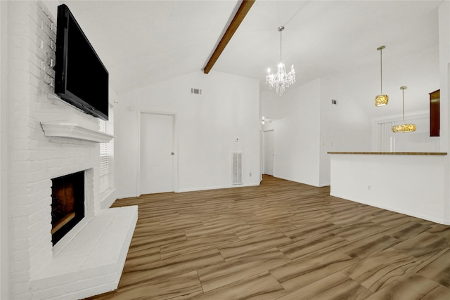 unfurnished living room with vaulted ceiling with beams, a notable chandelier, and a brick fireplace