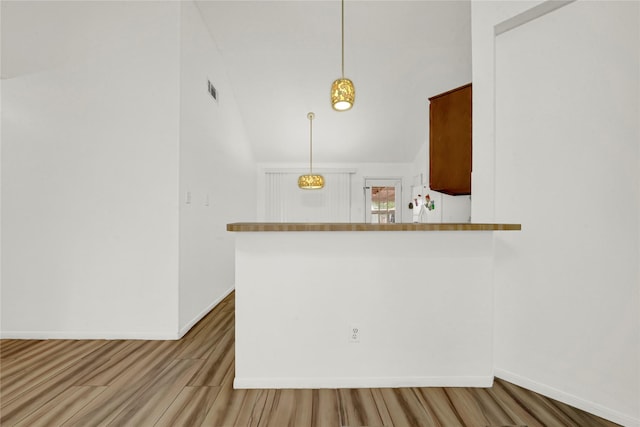 kitchen featuring light hardwood / wood-style flooring, kitchen peninsula, white fridge, lofted ceiling, and decorative light fixtures