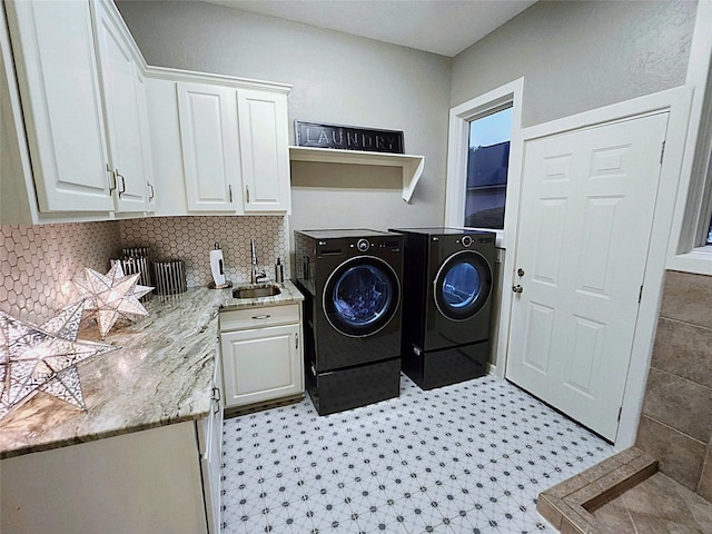 clothes washing area with washer and dryer, sink, and cabinets