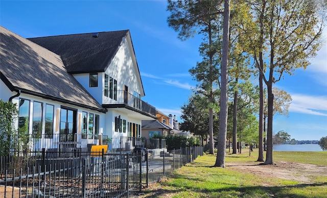 exterior space with a lawn, a water view, and a balcony