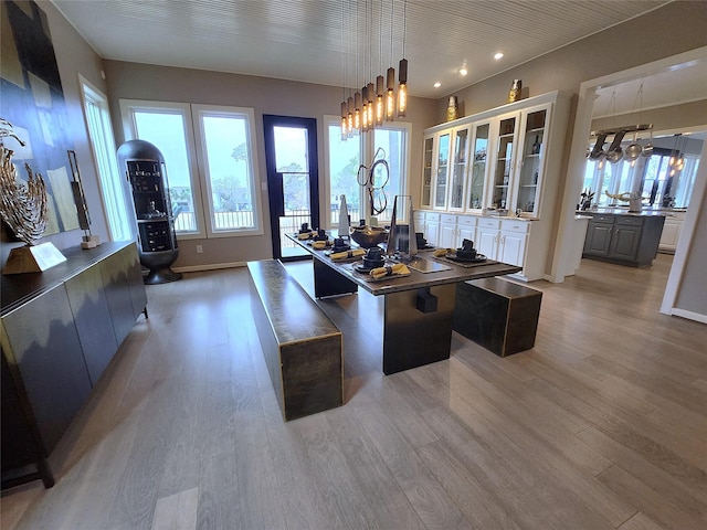 interior space featuring hanging light fixtures, hardwood / wood-style flooring, white cabinetry, and a center island