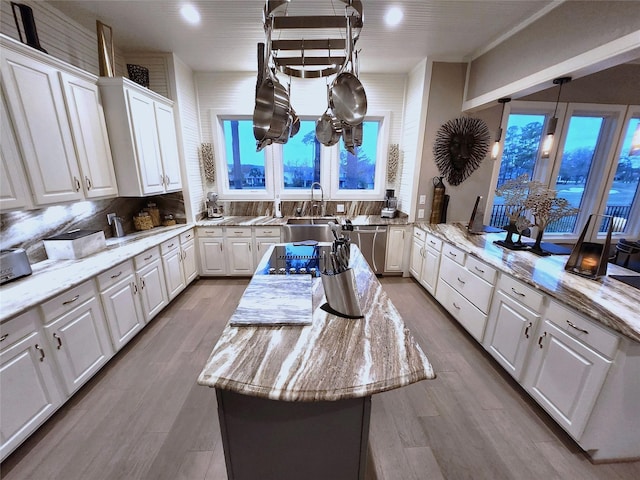 kitchen featuring decorative backsplash, light stone countertops, white cabinets, and a center island