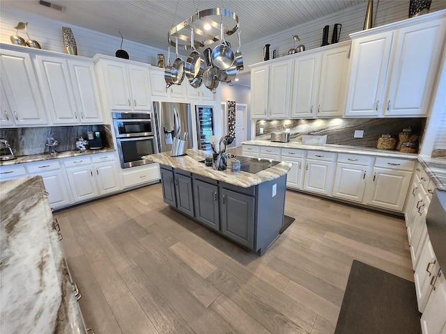 kitchen featuring hanging light fixtures, white cabinetry, stainless steel appliances, and a kitchen island