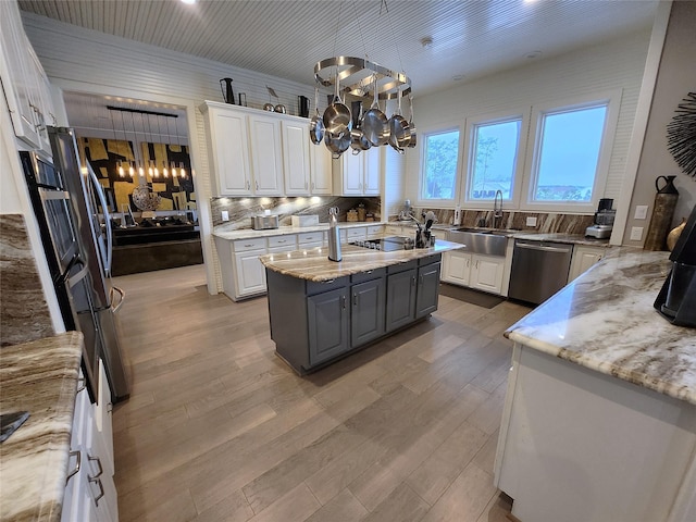 kitchen featuring stainless steel dishwasher, pendant lighting, white cabinetry, and a center island