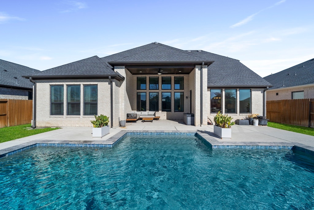 rear view of property featuring a fenced in pool, ceiling fan, and a patio