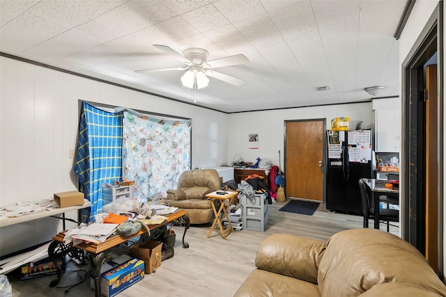 living room with ceiling fan, light wood-type flooring, and wooden walls