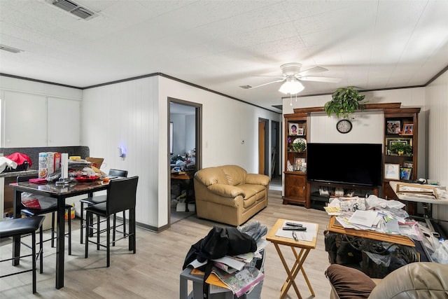 living room featuring ceiling fan, ornamental molding, and light hardwood / wood-style flooring