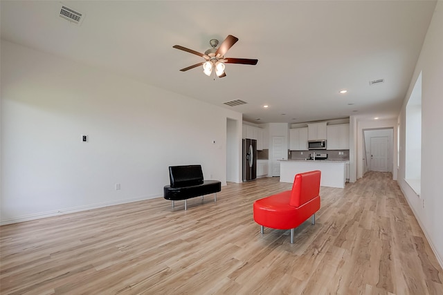 living room featuring light wood-type flooring and ceiling fan