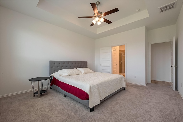 bedroom featuring ceiling fan, light colored carpet, and a tray ceiling