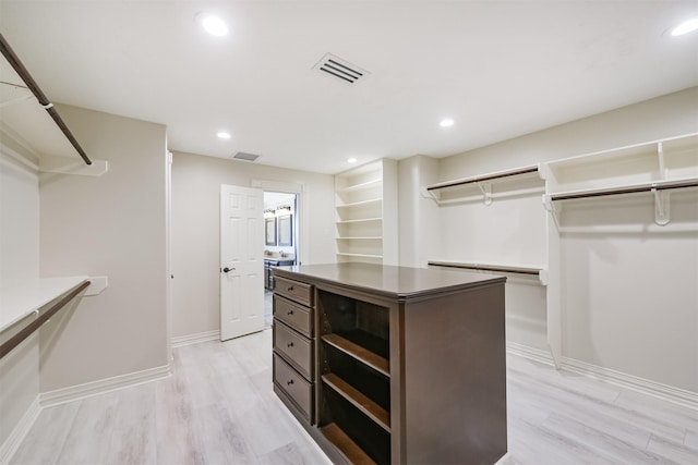 walk in closet with light hardwood / wood-style floors