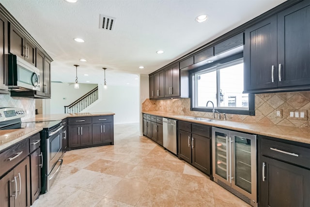 kitchen with decorative backsplash, stainless steel appliances, sink, pendant lighting, and wine cooler