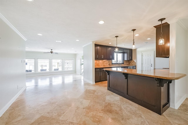 kitchen featuring ceiling fan, sink, decorative light fixtures, a kitchen bar, and decorative backsplash