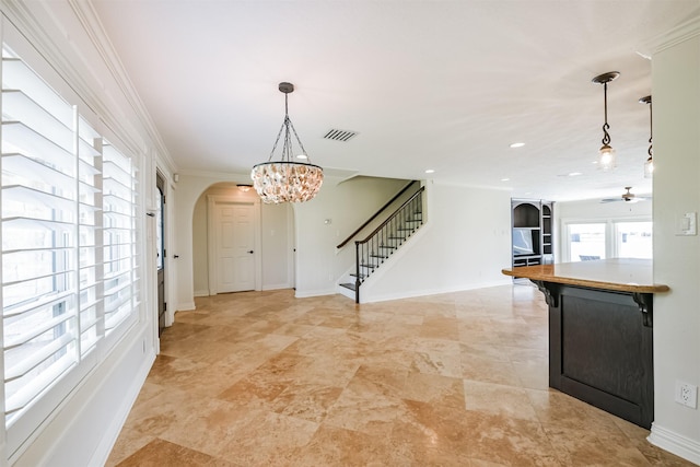 entrance foyer with ceiling fan with notable chandelier and ornamental molding