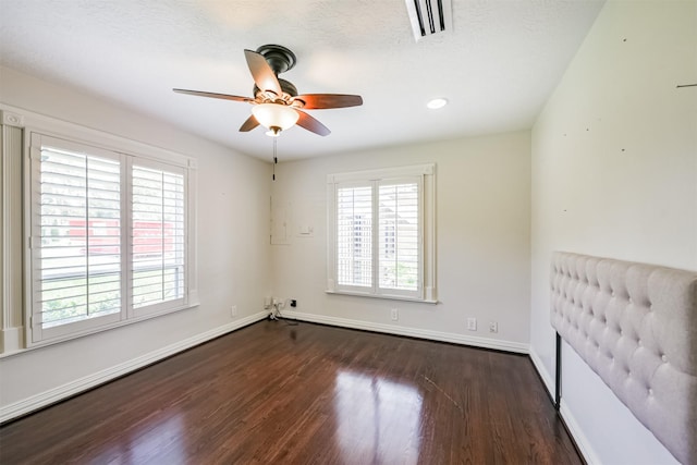 unfurnished bedroom featuring ceiling fan, dark wood-type flooring, and a textured ceiling