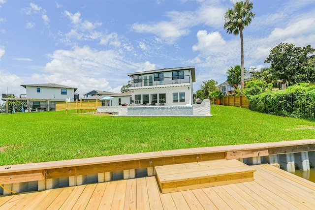 back of house with a deck with water view, a yard, and a balcony